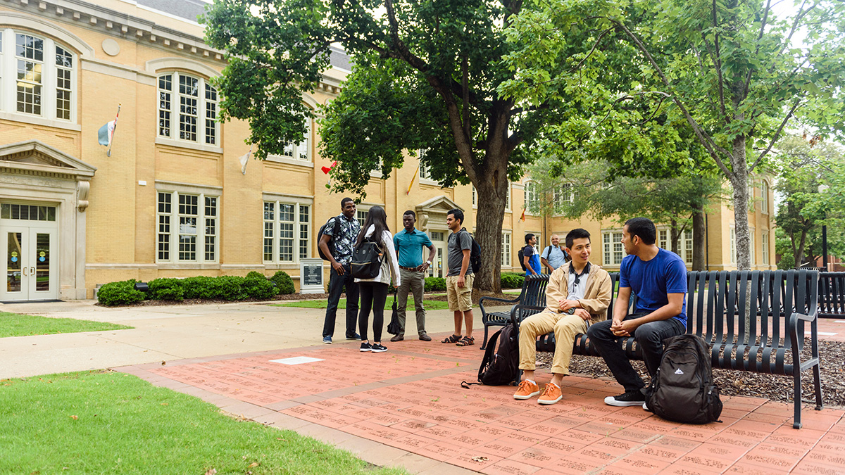 several groups of students converse outside of BB Comer Hall